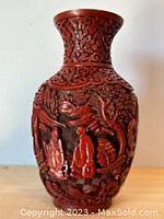 Front view of vivid red Chinese cinnabar vase showing detailed carvings of figures and scenery