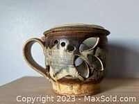 Side profile of pottery candle holder showing handle and decorative cut-outs