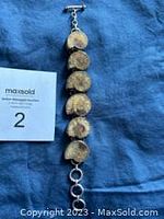 Full view of the sterling silver bracelet with round ammonite fossil links and toggle clasp on blue fabric background.