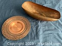 View of both copper pieces showing the plate with hammered edges and the elongated boat-form dish with patina.