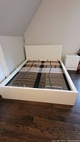 Front view of white MALM queen bed frame showing headboard and slatted base without mattress