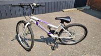 Full side and partial angle view of the Supercycle white and purple 24 inch bike showing overall frame and wheels.