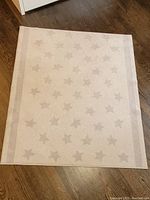 Image showing the full rectangular grey rug with star pattern and bordered edges, laid out on wooden floor.