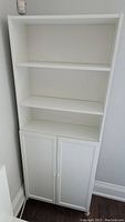 Full view of the assembled white IKEA BILLY/OXBERG bookcase with three open shelves and lower cabinet with closed doors.