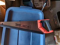 Photos showing a new TASK Tools 16 inch hand saw with ergonomic black and orange handle and protective blade cover labeled Barracuda.