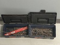 Two open Mastercraft plastic toolboxes displaying various sizes of drill bits and chuck keys inside.