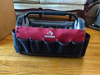 Front view of Husky 17 inch open tool tote showing red and black fabric with multiple exterior pockets and solid handle