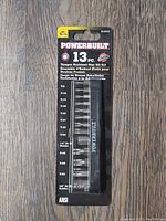 Front view of Powerbuilt 13-piece Tamper Resistant Star Bit Set in sealed packaging with visible bits and holders.