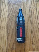 Full view of Retract-A-Bit tool showing black body with red branding and ergonomic grip.