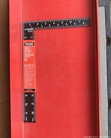 Steel utility square laid flat showing 12 inch and 8 inch measurement sides with white numbering on black surface.