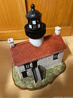 Showcasing the lighthouse figurine from an angled perspective highlighting texture, stairs, tower, and base details.