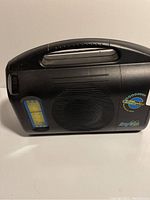 Front view of black BayGen wind-up radio showing speaker, handle, and frequency display.