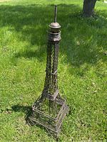 Full photo of the metal Eiffel Tower model standing on grass, showing overall shape and size.