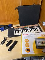 Overview photo showing Yamaha keyboard, charging dock, Amazon Firestick with remote, carrying case, and Kodak photo frame box.