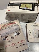 Boxed Magellan Maestro 5310 GPS with Pebble power bank wireless charger and ADS Instant Music device packaging