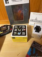 Photo of the 5 items including fitness watch, handheld game, Metal Earth model, Magnetic Poetry kit, and board game