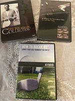 Three golf instructional DVDs displayed on a patterned surface: The Ben Hogan Collection, AJ Reveals the Truth About Golf, and How to Break 80 Hybrid Lower Your Golf Handicap Instantly.