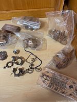 Overview of the mixed wooden and metal puzzles arranged on a wooden surface, some items wrapped in plastic bags.