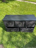 Front view of black fabric drawer storage cabinet set on grass, showing three smaller drawers on top and two larger drawers on bottom.