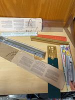 Photo showing various vintage rulers, slide rule, protractor, and templates spread out on a surface.