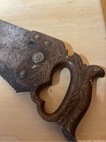 Close-up of ornate carved wooden handle with leaf patterns and eagle head.