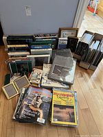 Wide view of collection showing hardcover and softcover fishing books stacked along wall, group of Canadian Flyfisher magazines in boxes.