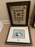 Both framed items displayed against wall on floor