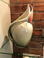 White porcelain butterfly vase with pastel-colored wing handle against brick background.