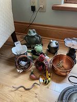 Overview of all lot contents including frog figurines, flower pots, toadstools, and small animal decorations arranged on floor.