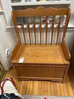 Front view of the oak hall bench showing the slatted backrest and seat with wear marks.
