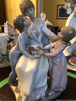 Full view of figurine showing mother seated with two children presenting a gift