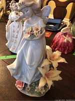 Full view of the white porcelain fairy figurine with pastel flowers and lilies at base