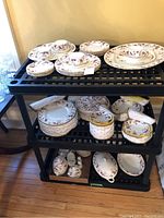 Full set arranged on cart with plates, teacups, serving bowls, covered pieces, teapot, and small accessories.
