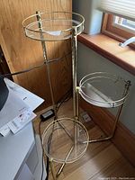 Full view of the brass plant stand with two glass trays positioned near a window.