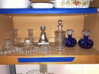Shelf showing all the candlesticks and perfume bottles together.