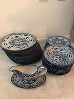 Overview of stacked dinner plates on left, salad plates on right, soup bowls, and gravy boat with underplate in front