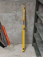 48 inch yellow aluminum box level leaning against a concrete wall, showing full length and bubble vial windows
