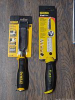 Photo of Dewalt chisel and Stanley FatMax jab saw in packaging on wood floor.