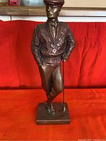 Full front view of the 17 inch Austin Golfer ceramic sculpture painted bronze and copper tone on red background