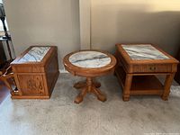 Three-piece wood and marble table set showing all tables side by side on carpeted floor.