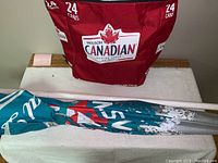 Photo showing the Molson Canadian red backpack cooler with logos and a folded interlocking umbrella with Molson Canadian branding and wooden pole.