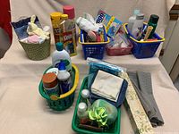 Overview photo of multiple plastic baskets filled with assorted bathroom cleaning and personal care items arranged on a table.