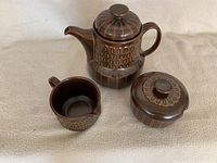 Photo showing the three pieces of the set: teapot, creamer, and sugar bowl with lid on a neutral background.
