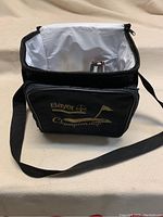 Black Bayer Championship cooler bag with shoulder strap, open, showing interior