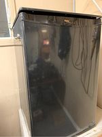 Front view of black Danby compact refrigerator with a single door and top handle.