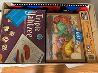 Top view of box showing Triple Yahtzee game box, 300-piece jigsaw puzzle titled 'Gateway to Yellow Stone' with dinosaur art