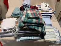 Overview of all sheets and blankets in the set stacked on a couch.