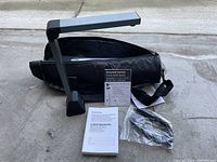 Folded ScanLine document camera with black carrying case, user manual, quick start guide, and cables on pavement.