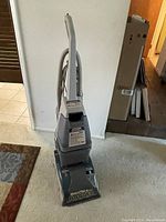 Full view of Hoover SteamVac Deluxe carpet shampooer upright with attached hose and cord.