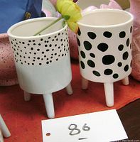 Two ceramic planters side by side showing different polka dot patterns and their three-legged design.